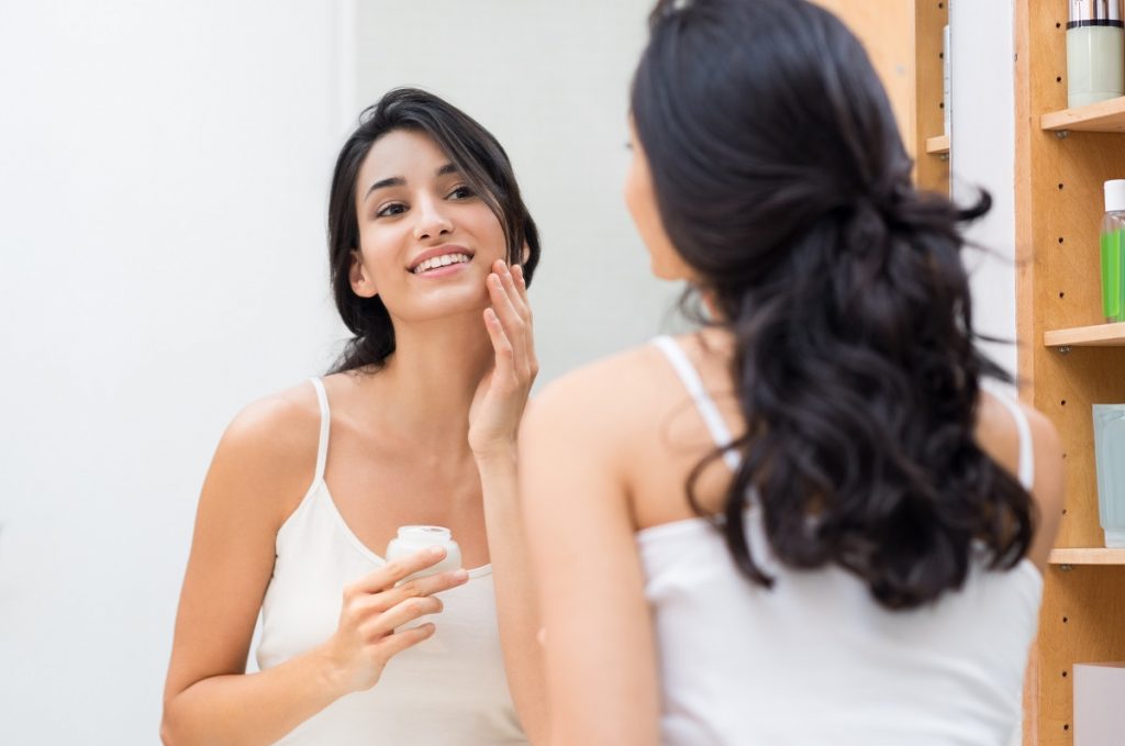 Woman applying cream on face