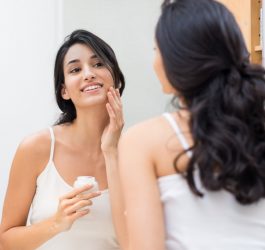 Woman applying cream on face